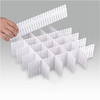 White plastic grid organizer with a hand lifting one of its sections on a gray background