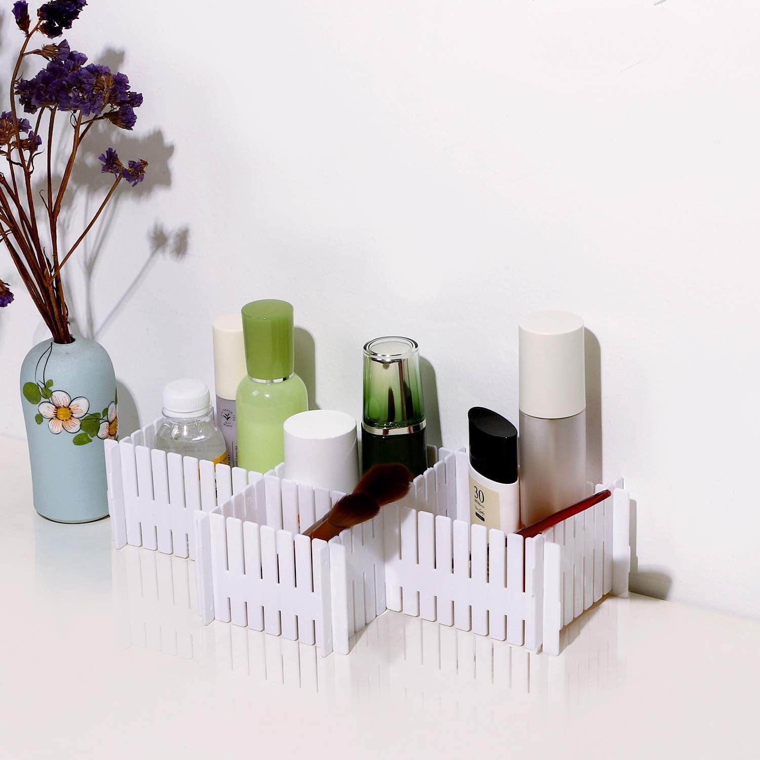 White decorative basket with various items including bottles and a vase on a white surface.