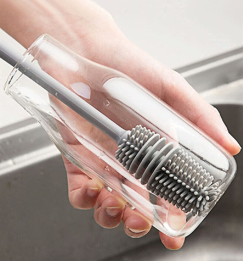 Hand holding a clear plastic case with a gray bristle brush inside.