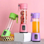 Three portable blenders with colorful lids on a pink background